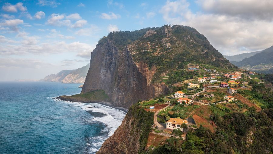 Steile Küstenhänge und Häuser von Faial mit der Penha de Águia im Hintergrund
