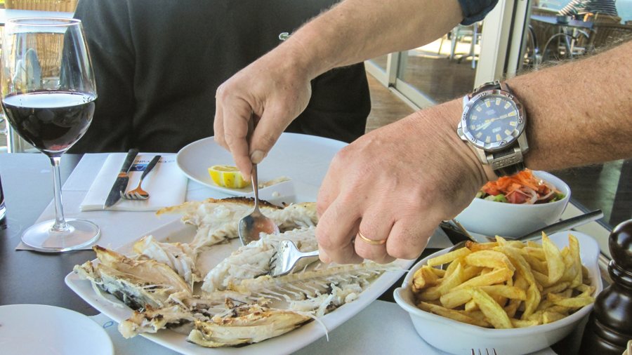 Gegrillter Fisch mit Pommes frites wird am Restauranttisch serviert